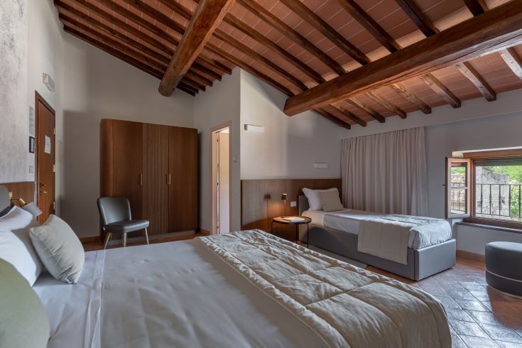 Ein gemütliches Zimmer in einem historischen Palast mit Holzbalken und Blick auf die umbrische Landschaft.