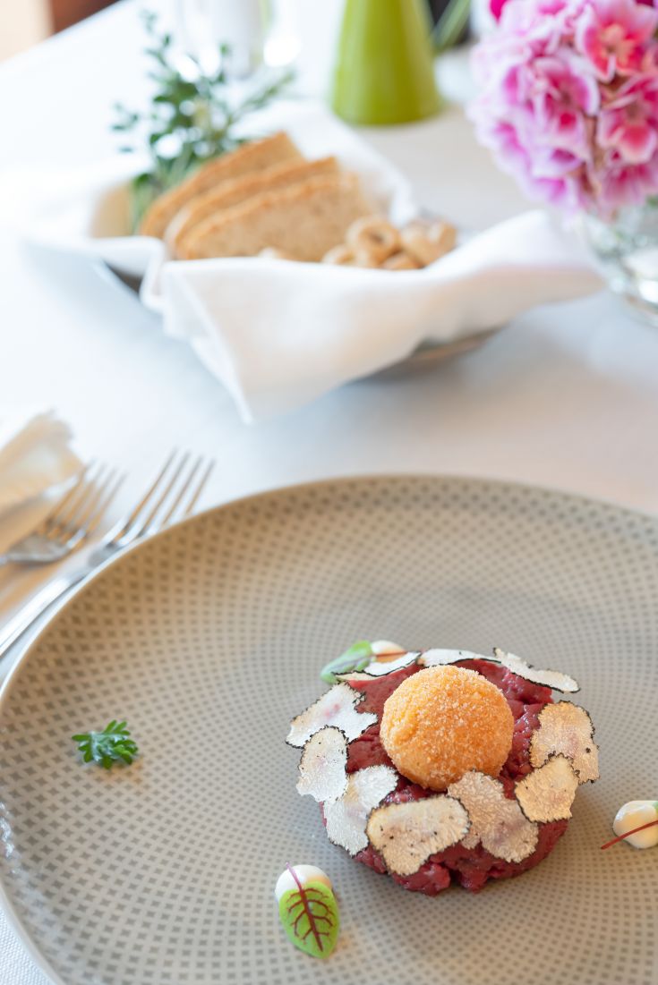 Ein raffiniertes Gericht mit Trüffel und Eigelb, serviert mit Brot und floralen Dekorationen.