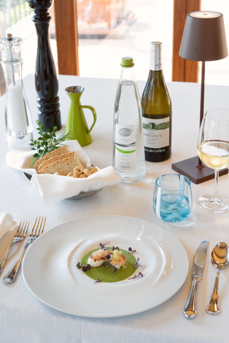 Ein raffiniertes Gericht, das in einem Restaurant serviert wird, mit Wein und Mineralwasser daneben.
