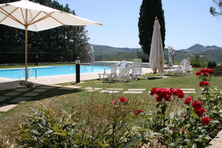 Ein Pool, umgeben von Natur, mit Blick auf Hügel und Blumenpflanzen, die den Raum schmücken.