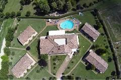 Blick auf das Hoteldorf Le Macerine, umgeben von Grünflächen und mit einem Schwimmbad.