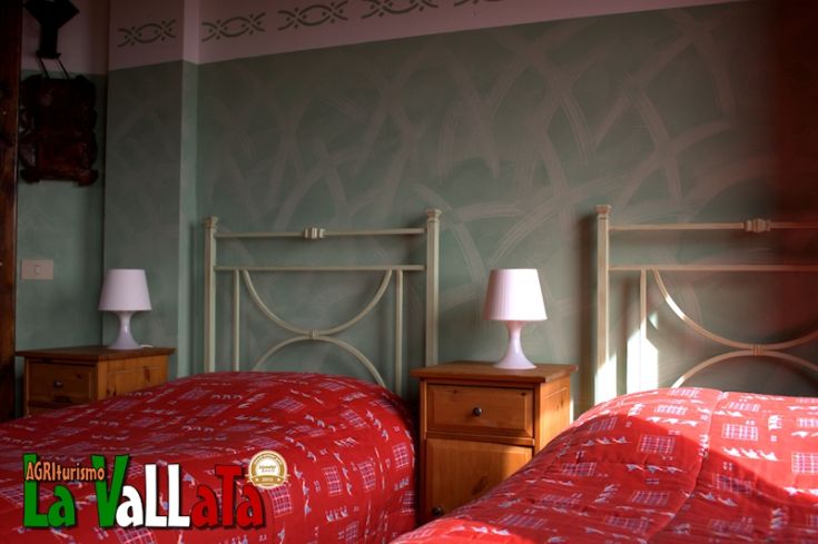 Camere spaziose con letti matrimoniali, arredamento in legno e tonalità verdi, situate in un ambiente tranquillo dell'Umbria.