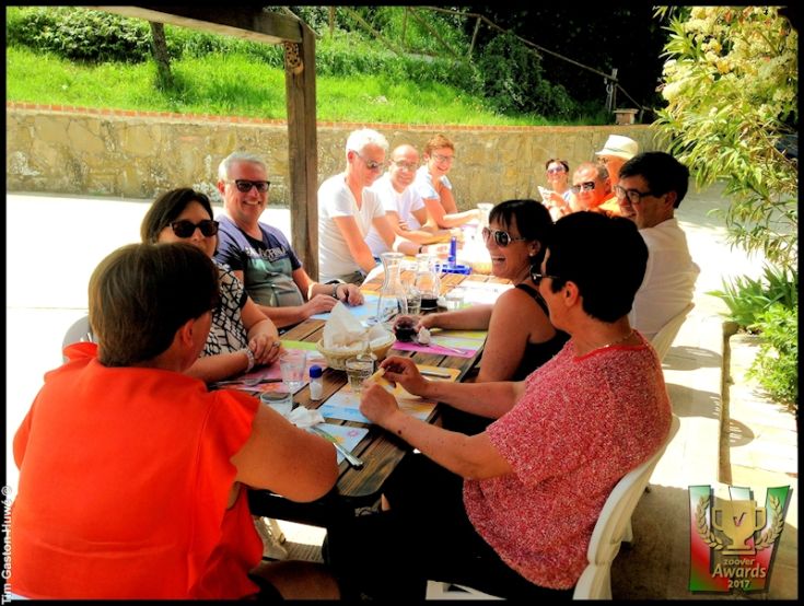Un gruppo di persone sedute attorno a un tavolo all'aperto, approfittando del tempo insieme in un ambiente naturale.