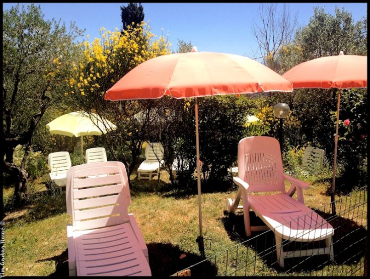 Un'area all'aperto con lettini e ombrelloni, circondata da vegetazione. Un luogo tranquillo per il relax.