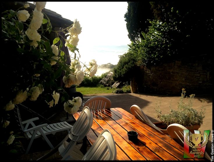 Un'area esterna tranquilla con un tavolo in legno e fiori bianchi che decorano il giardino.