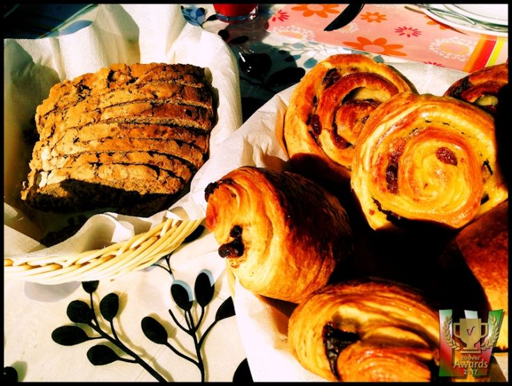 Dolci appena sfornati: panini e una fetta di pane casereccio mostrati su un tavolo.