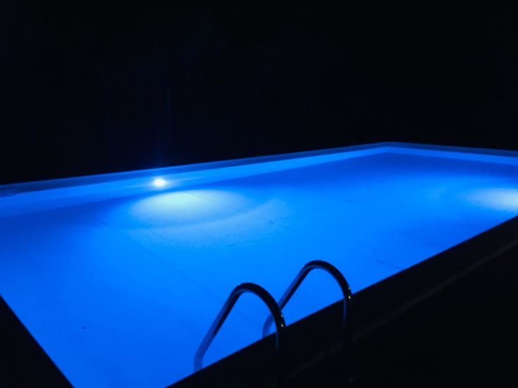 Piscina splendente in un contesto notturno sereno, circondata da un'atmosfera rilassante.