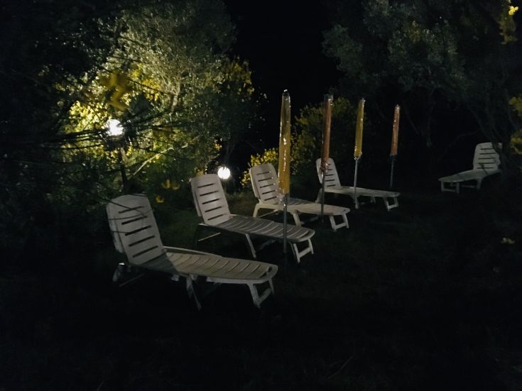 Un giardino notturno con lettini e luci soffuse, che creano un'atmosfera rilassante in un palazzo umbro.