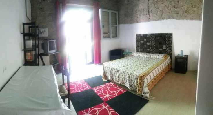 Spazio semplice con letto matrimoniale, ben illuminato dalla porta finestra.