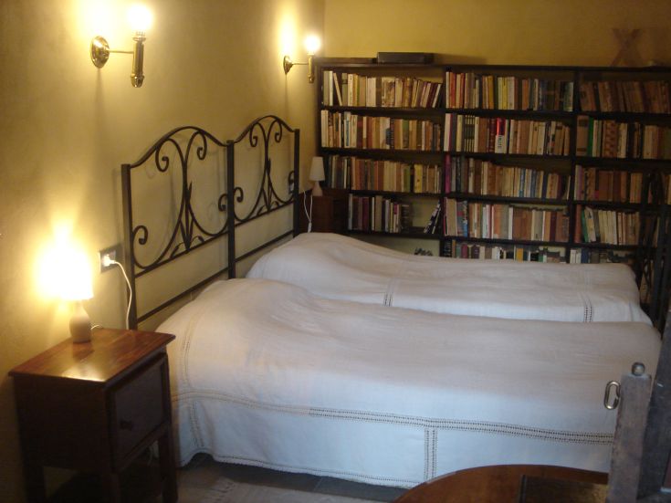 Stanza semplice con letti singoli, una libreria e una luce morbida.