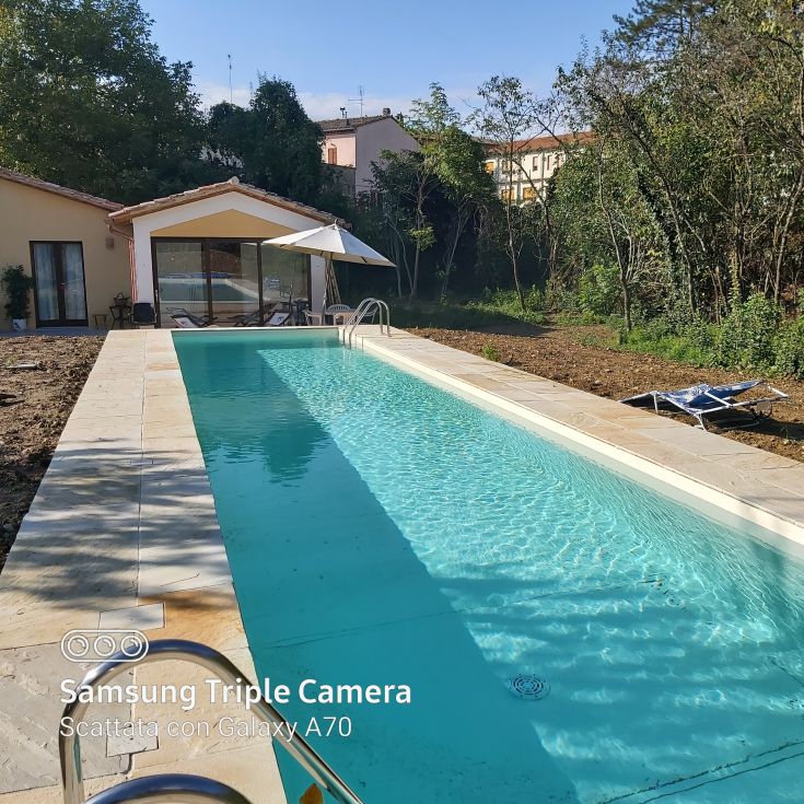 Una villa moderna circondata da alberi e spazi verdi, con una piscina in un ambiente sereno, perfetta per momenti di relax.