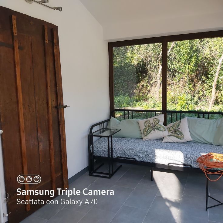 Un'area soggiorno accogliente in un appartamento, caratterizzata da elementi semplici e un'atmosfera confortevole, con affaccio su un'area verde.