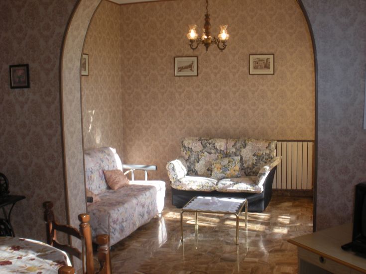 A simple and bright living room furnished with floral elements and featuring pleasant natural light.