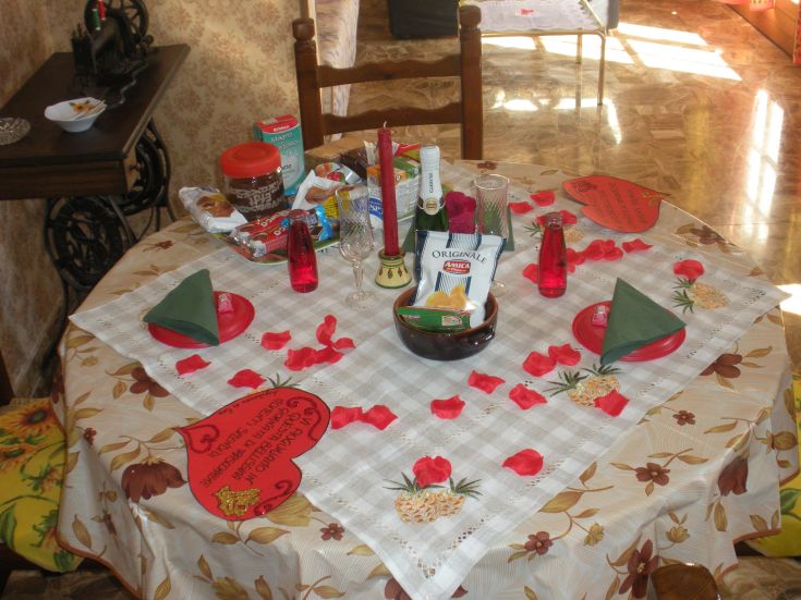 A simple table adorned with rose petals and candles, perfect for a romantic candlelit dinner.