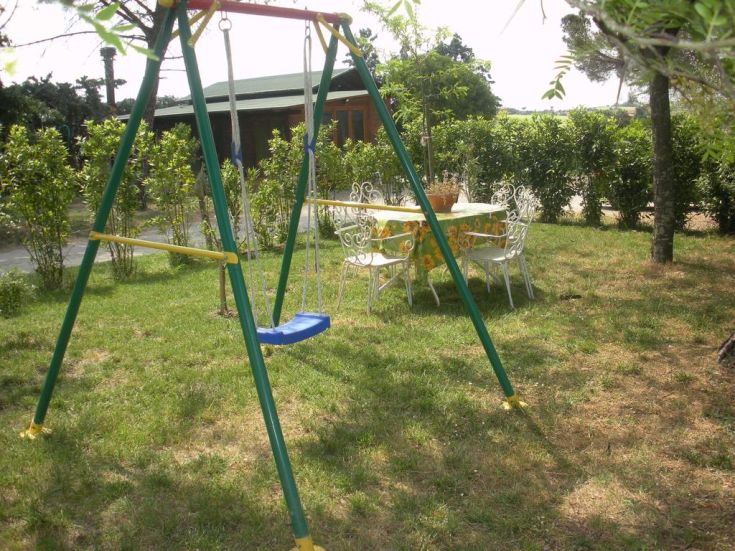 An outdoor green area with a swing and a garden table, perfect for relaxing moments.