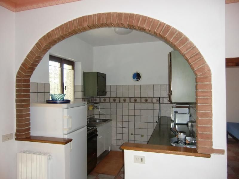 Spacious and well-lit kitchen with brick arches, ideal for a relaxing stay in a farmhouse.