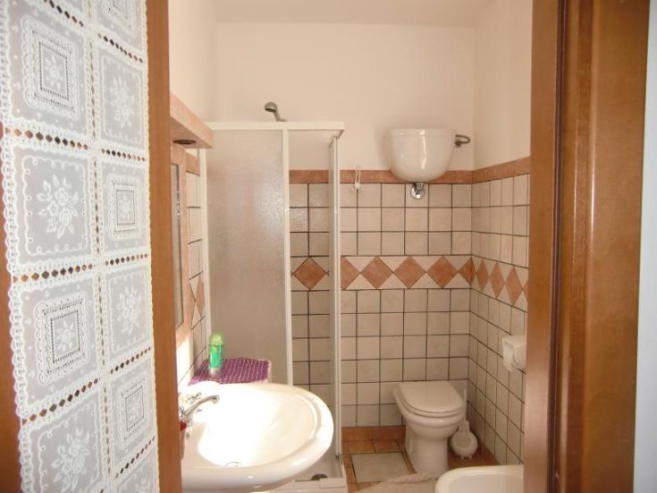 Une salle de bain lumineuse avec douche, toilettes et lavabo, située dans un bâtiment ombrien.