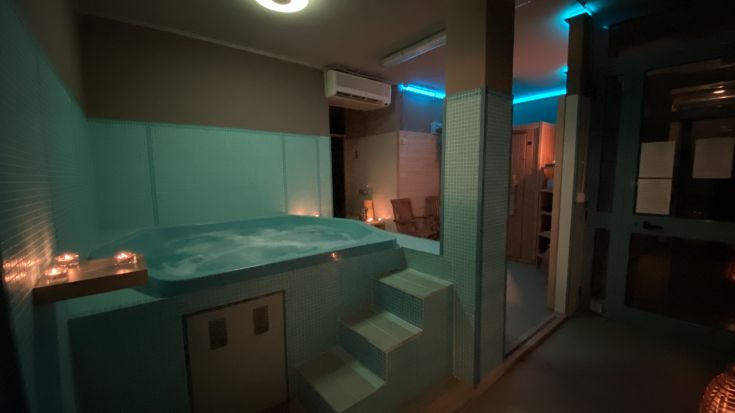 Un edificio accogliente in una zona benessere con vasca idromassaggio e illuminazione soft, creando un'atmosfera rilassante.