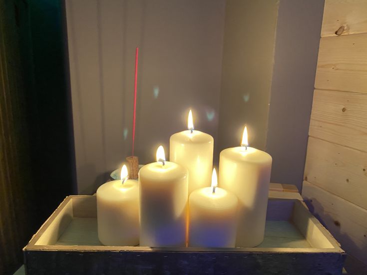 Un gruppo di candele bianche accese su un tavolo, creando un'atmosfera serena e accogliente.