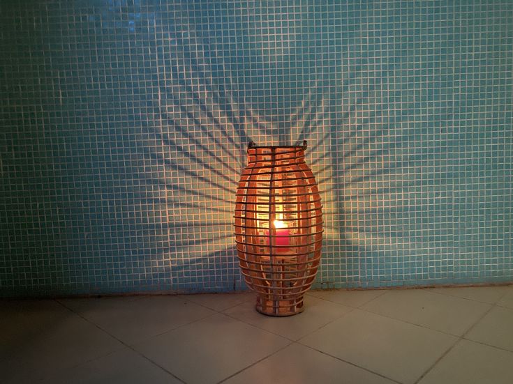 Lampada in vimini emette luce creando ombre sulla parete blu.