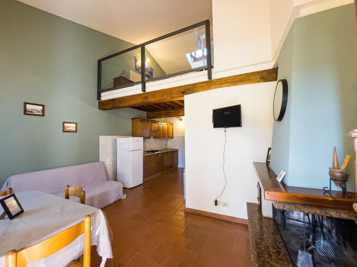 Soggiorno con cucina e soppalco, arredato in modo semplice e funzionale, adatto per una fuga tranquilla.