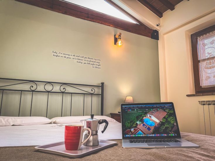 Camera accogliente con un laptop e una tazza di caffè su un tavolo, adatta per lavorare o rilassarsi.