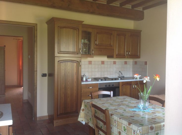 Cucina accogliente con armadi in legno e un tavolo, perfetta per trascorrere momenti in compagnia.