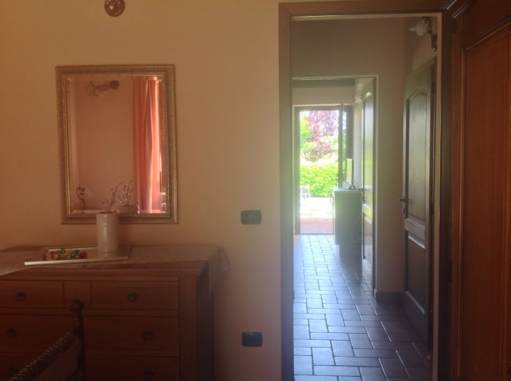 Interno di un agriturismo con un corridoio che porta a un ampio giardino. Ideale per una vacanza tranquilla.