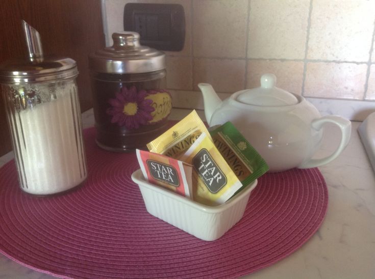 Un angolo intimo per gustare un tè, completo di zucchero e una semplice teiera bianca.