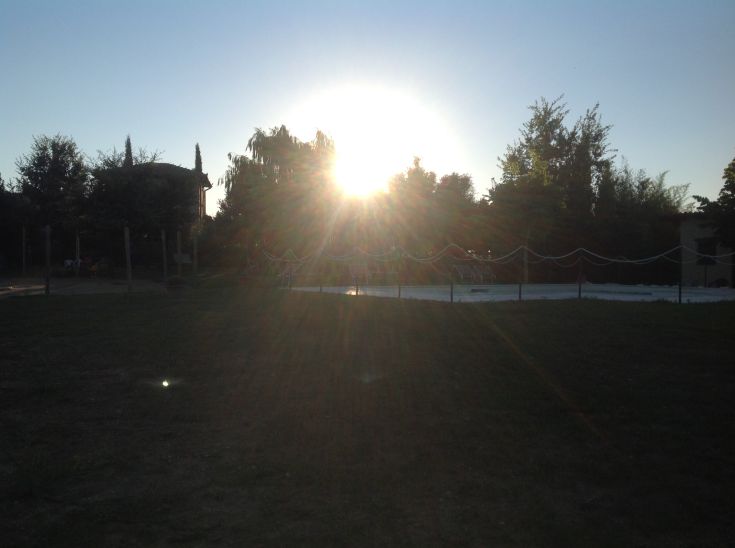Un tramonto delicato si diffonde su un agriturismo circondato da aree verdi, perfetto per momenti di relax.