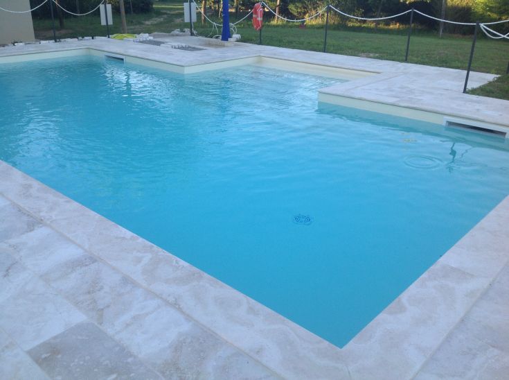 Una piscina di colore azzurro immersa in un giardino curato, perfetta per momenti di relax.