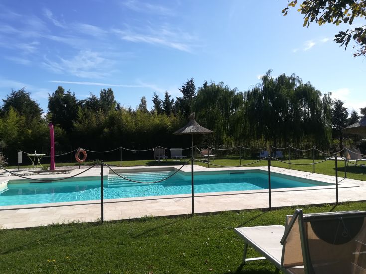 Un giardino tranquillo con piscina, circondato da vegetazione e aree per il relax.