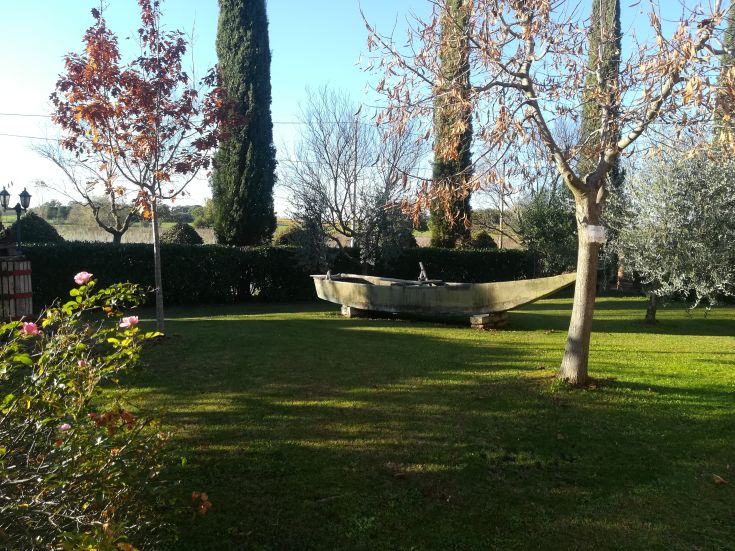 Un giardino ben tenuto con alberi e una barca di legno, situato in un ambiente tranquillo tipico della campagna umbra.