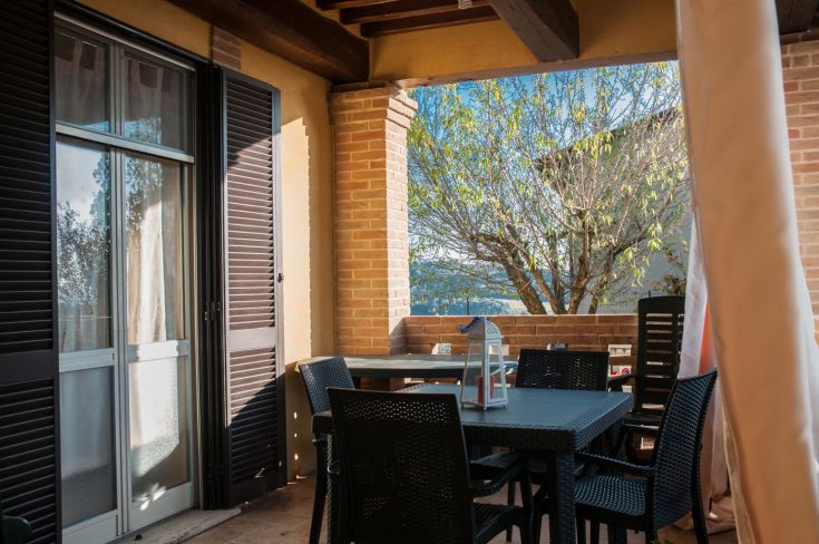 A cozy patio with a rattan table, surrounded by lush greenery.