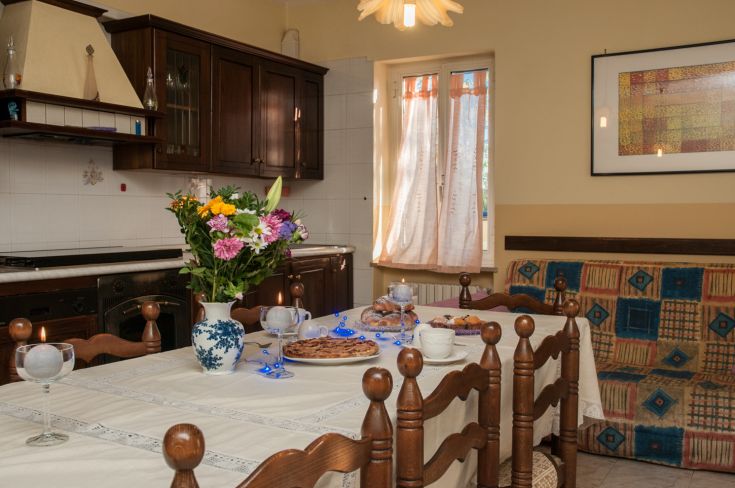 A simple and cozy kitchen with a set table and a bouquet of fresh flowers.