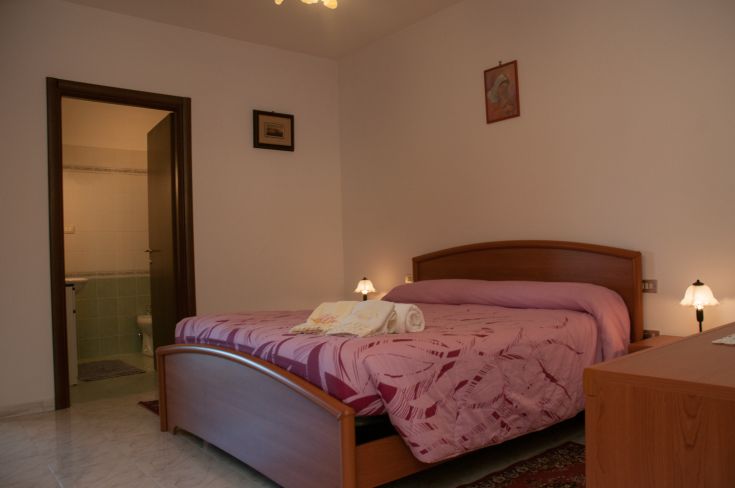 Bright master bedroom with a large bed and adjacent private bathroom.