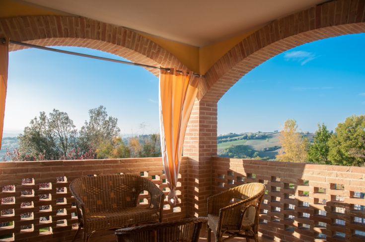 A simple terrace overlooking green hills and a clear sky.