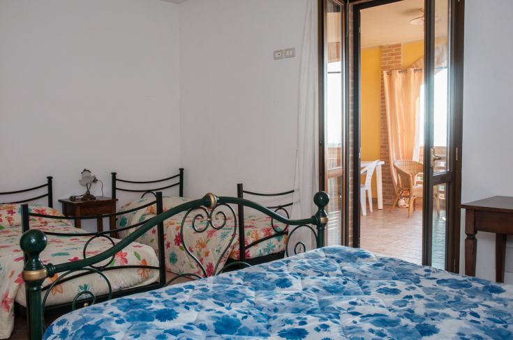 Simple room with canopy beds and access to a sunny terrace.