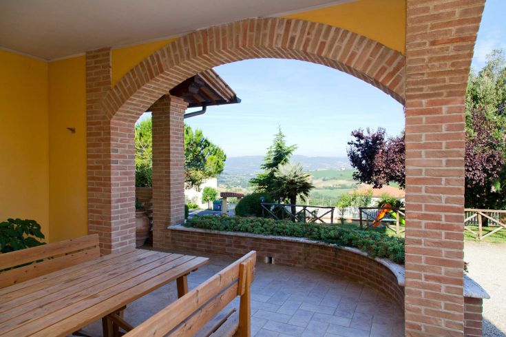 A cozy terrace providing a panoramic view of a green and hilly landscape.
