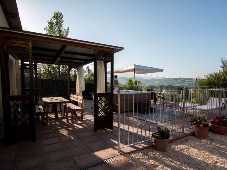 An outdoor space with a gazebo and table, overlooking a scenic view of surrounding hills.