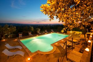 Piscina situata in un ampio giardino ben curato, con vista sul paesaggio al tramonto.