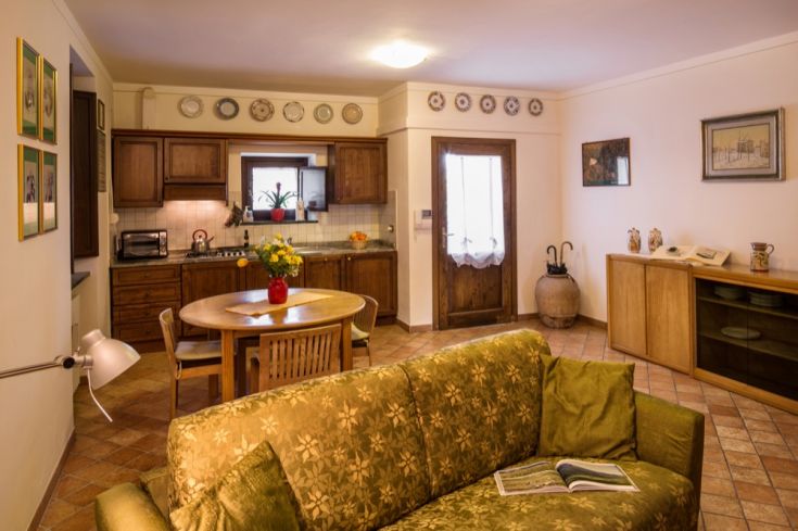 Cucina spaziosa e soggiorno confortevole con arredi in legno e accenti rustici, ideali per una pausa tranquilla.