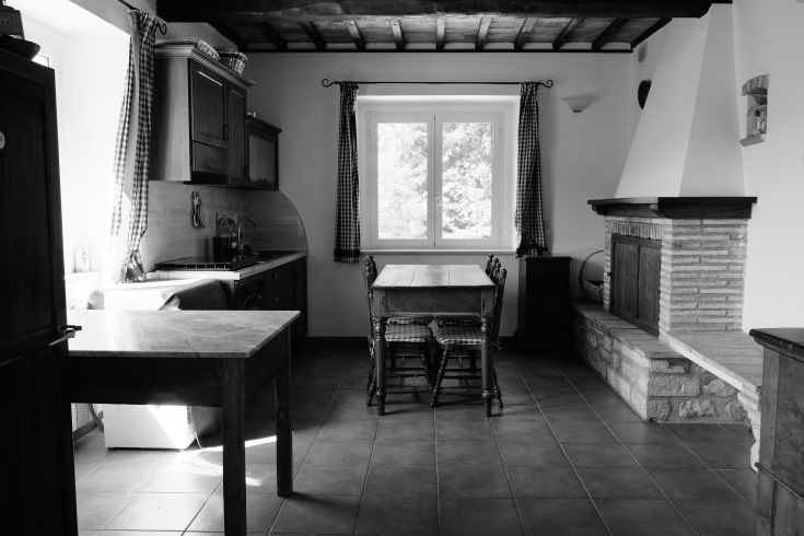 Renovated kitchen in a building, featuring a wooden table and a fireplace. Bright and cozy atmosphere.