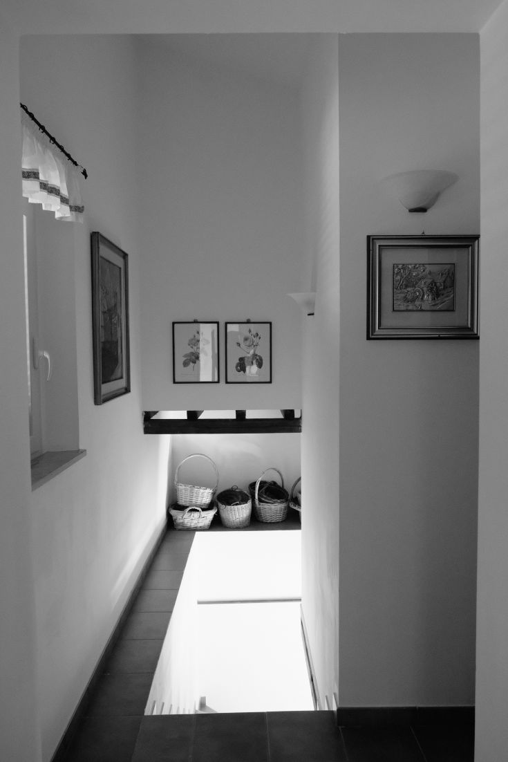 A bright hallway filled with natural light, featuring paintings on the walls and neatly arranged baskets.