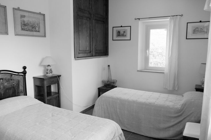 A room with single beds, featuring a sober design and a window providing natural light.