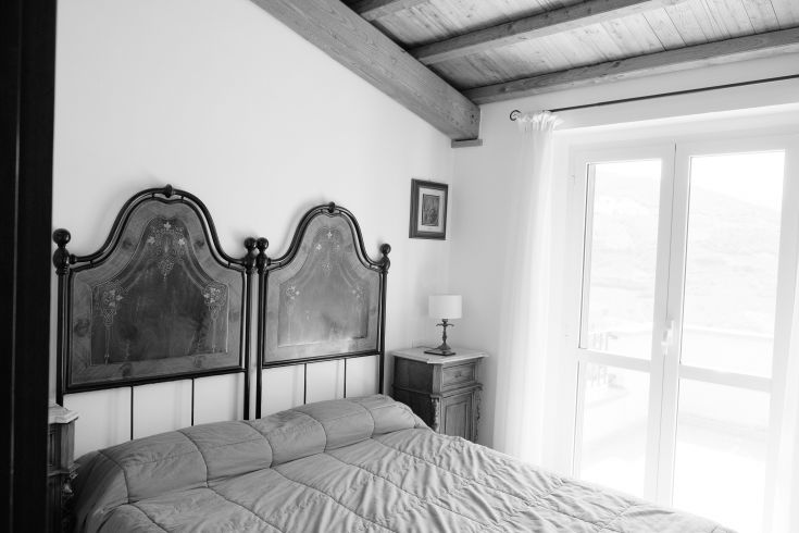 Bedroom with a wooden headboard overlooking a green landscape.