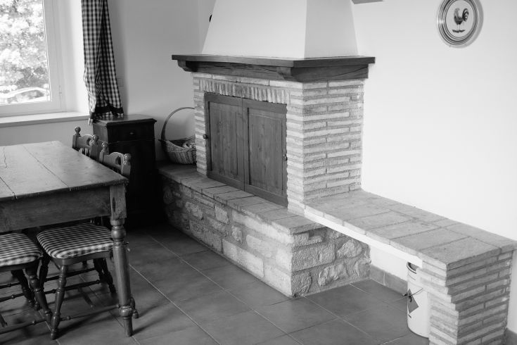 Cozy kitchen interior featuring a stone fireplace and light wooden furniture.