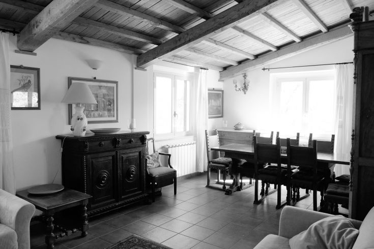Spacious living room with a dining table and wooden furniture, featuring natural light that makes the space inviting.