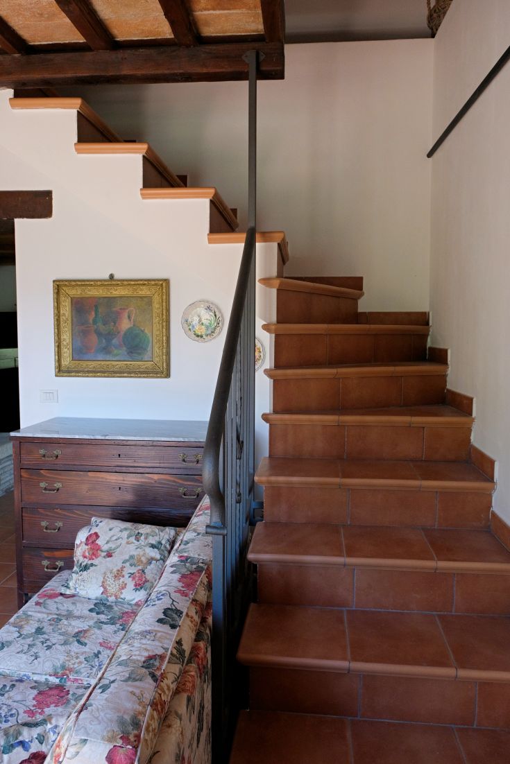 A cozy, sober interior featuring terracotta stairs and classic furniture.