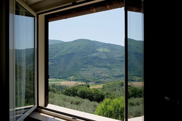 A view of green hills through a window of a typical country farmhouse.